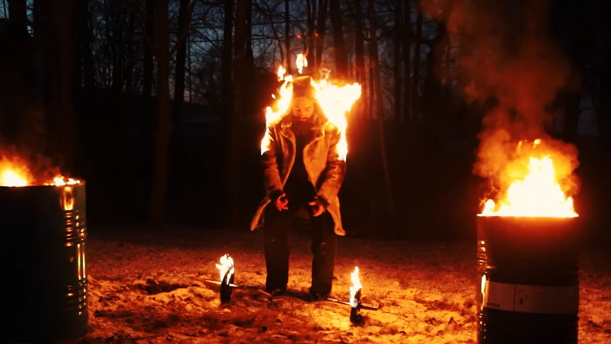A full body burn at night between two fire barrels